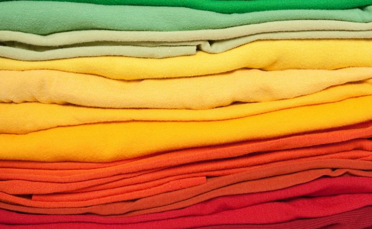 A stack of folded clothes in seasonal colours, from green to yellow, orange and red.